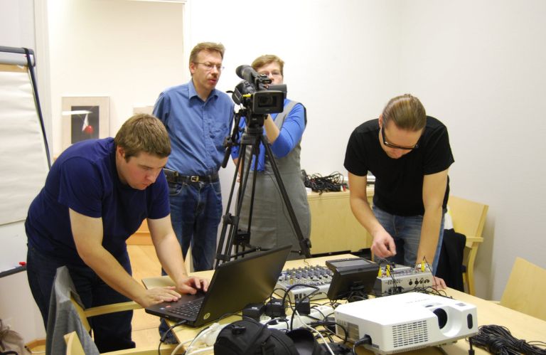 Välkkeen jäsenistä koostuva kuvausryhmä testaamaassa videokameraa sisätiloissa.